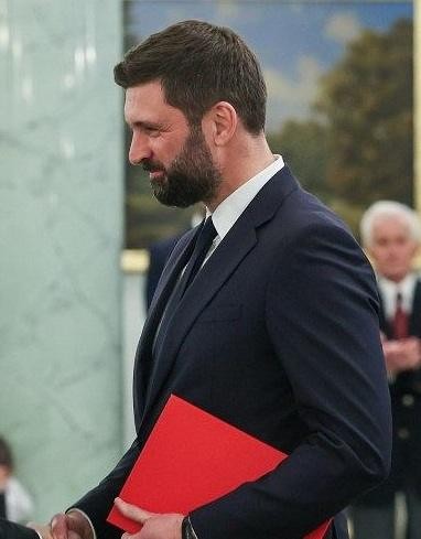 Nikodem Rachoń w profesjonalnym otoczeniu, symbolizującym jego rolę w polityce międzynarodowej i karierze zawodowej.