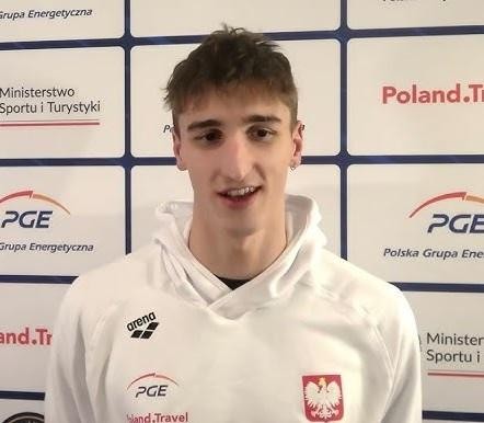 Ksawery Masiuk podczas wyścigu grzbietowego, z determinacją na twarzy i rozpryskującą się wodą.