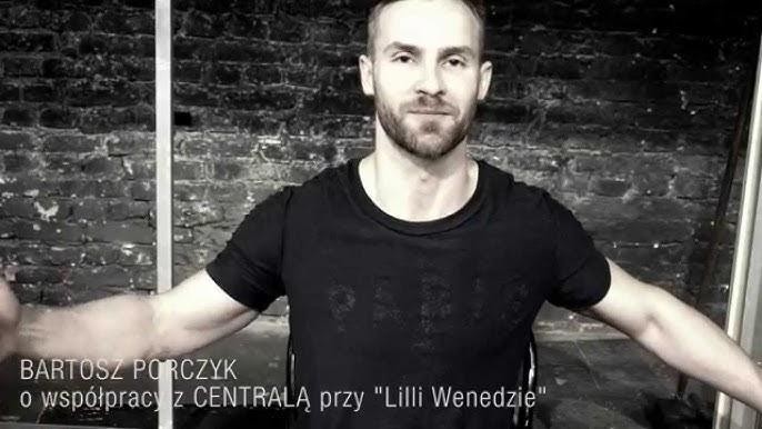 Bartosz Porczyk na scenie podczas występu, z mikrofonem, ukazujący jego umiejętności wokalne i aktorską interpretację piosenki, z dynamicznym oświetleniem scenicznym.