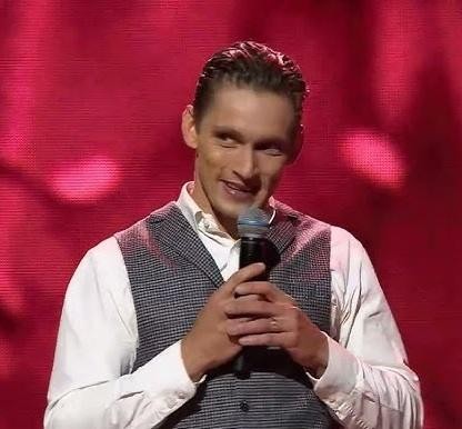 Filip Gurłacz tańczy na scenie w dynamicznej pozie, na tle rozmytych świateł scenicznych, ukazując energię występu.