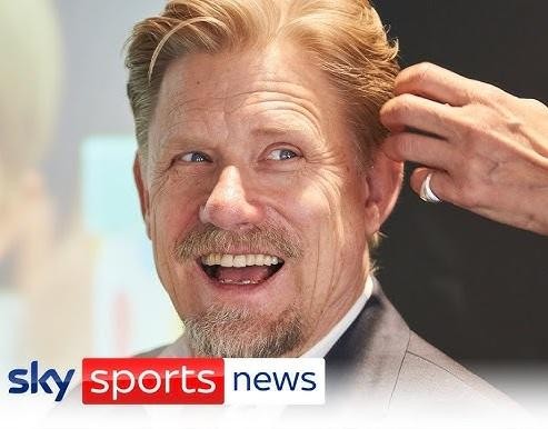 Peter Schmeichel z pucharem Ligi Mistrzów, uśmiechnięty na tle świętującego Old Trafford po zdobyciu potrójnej korony w 1999 roku.