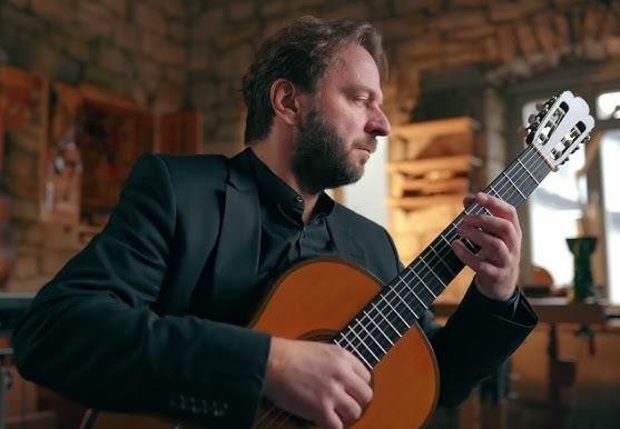 Zbliżenie na dłonie Marcina Dylli grające na gitarze klasycznej, podkreślające precyzję i technikę.