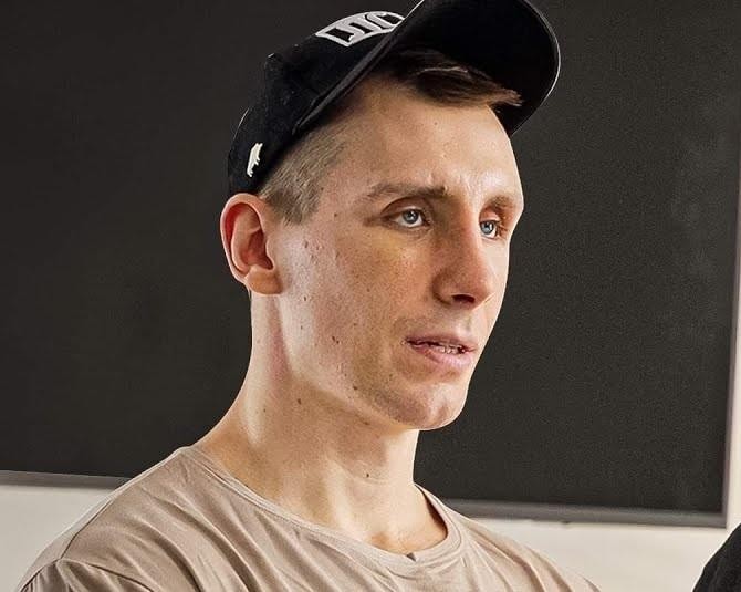 Michał Owczarzak (Owca WK) przeglądający Instagram na smartfonie, w tle siłownia, symbolizujący jego aktywność online.