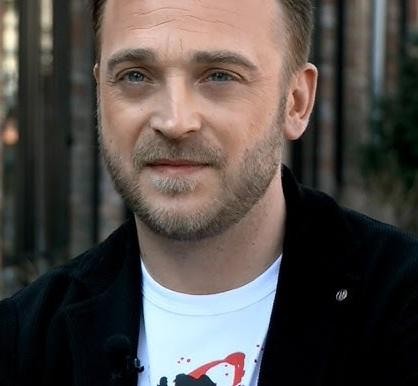 Mateusz Gessler podczas gotowania w kuchni, prezentujący swoje umiejętności kulinarne.