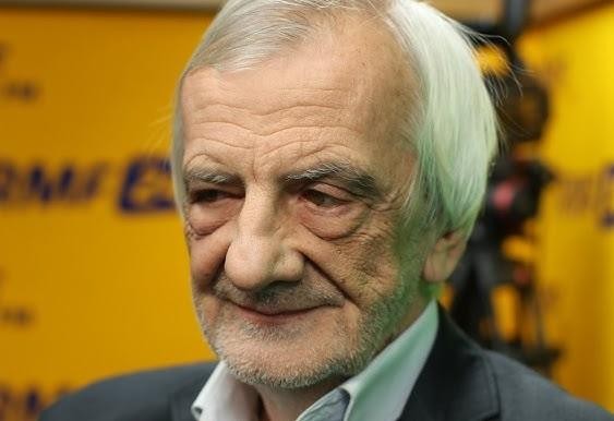 Ryszard Terlecki podczas debaty publicznej lub przemówienia, z ekspresyjnymi gestami, w tle rozmyte postacie.