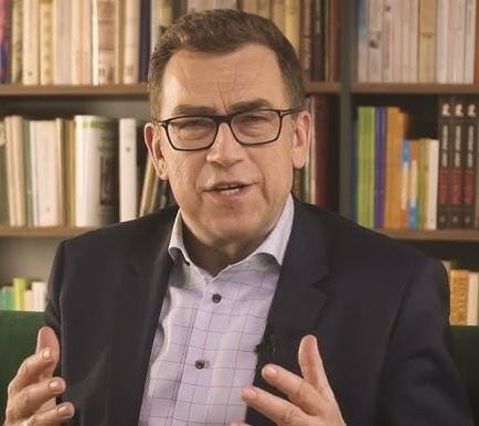 Maciej Orłoś podczas wystąpienia publicznego, dziennikarz i prezenter w akcji, charyzmatyczny.