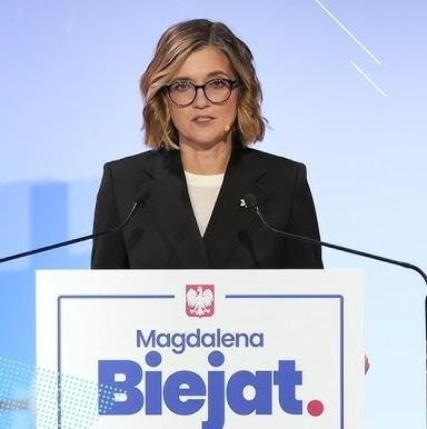 Magdalena Biejat podczas debaty parlamentarnej lub wystąpienia publicznego, z ekspresyjnym gestem, symbolizującym zaangażowanie i przekonanie.