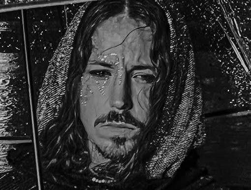 Michał Szpak w zbliżeniu, z długimi włosami i w charakterystycznym stroju, o intensywnym wyrazie twarzy.