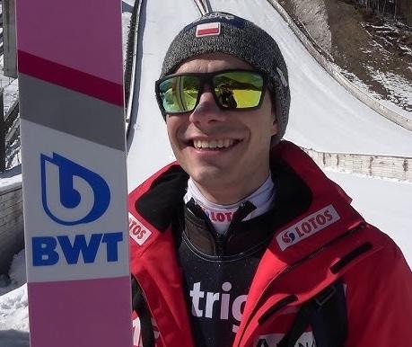 Jakub Wolny podczas treningu, skupiony i zdeterminowany, w tle rozmazany widok obiektu sportowego.